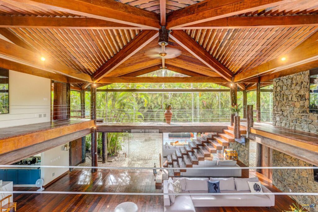 TV na parede de pedra vista pela sala de estar, a cozinha e a área da piscina