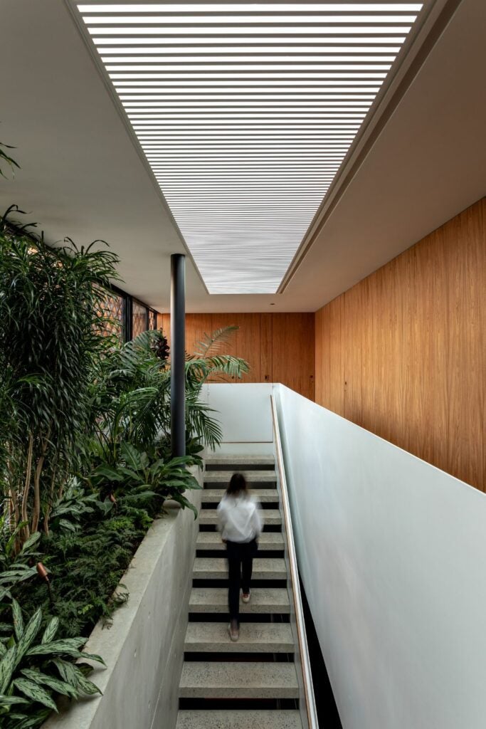 Uma generosa claraboia garante luminosidade permanente e a escada conecta os pavimentos