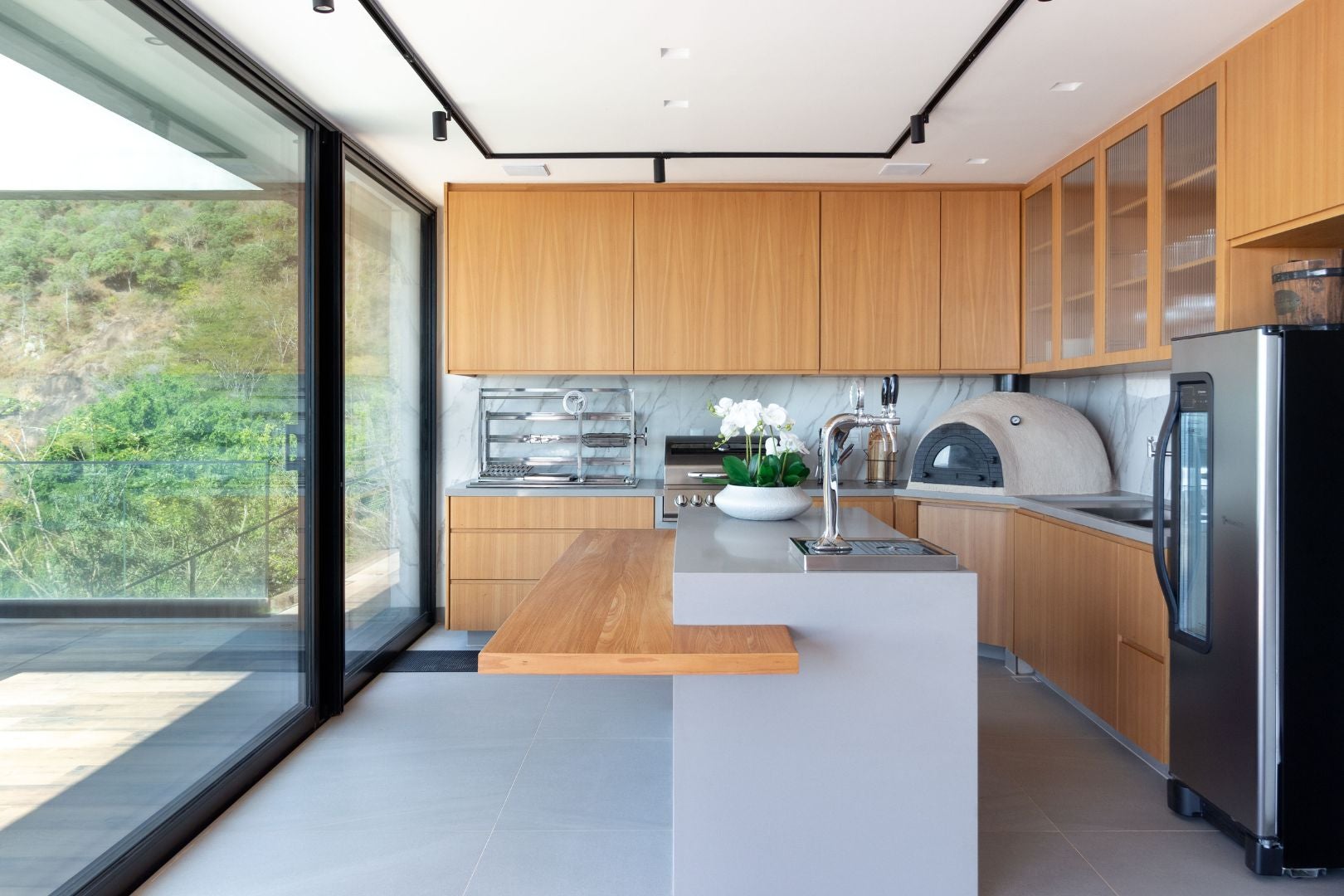 Espaço gourmet, separado da cozinha por portas deslizantes, conta com forno de pizza, churrasqueira a gás e a carvão e torre de chope