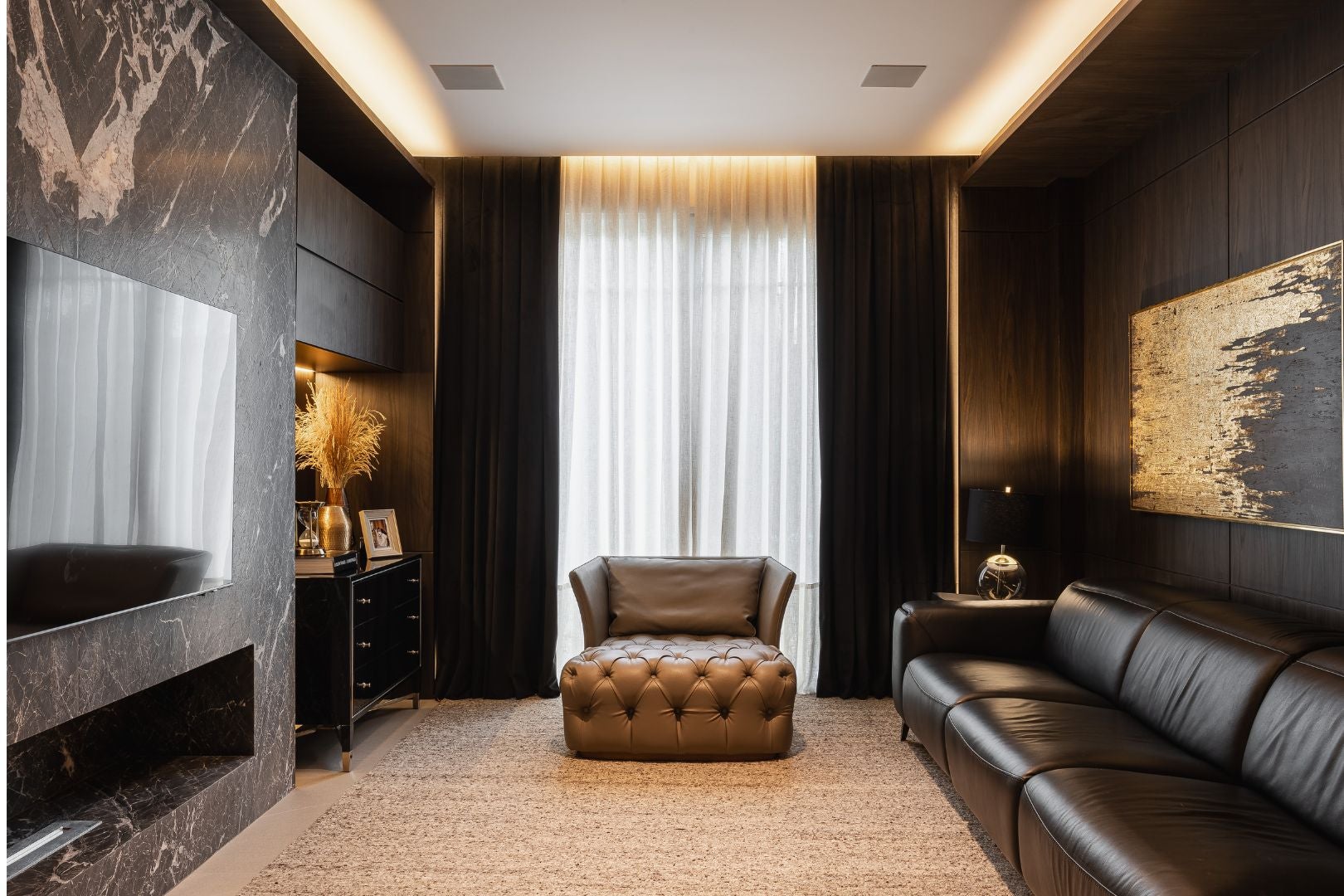 No home theater, materiais nobres em evidência: paredes revestidas de madeira ebanizada e mármore